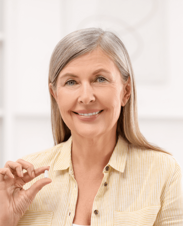 Woman smiling holding a pill